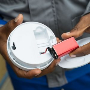 hands holding smoke detector with battery removed